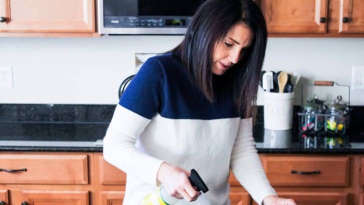 AnnMarie cleaning kitchen island with spray cleaner