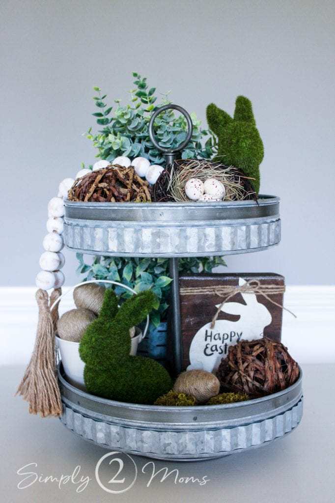 Decorating Farmhouse Trays for Spring | www.simply2moms.com | #tieredtray #springtray #rusticwoodtray #galvanizedtieredtray #mossbunnies #flockedbunnies #naturalspringdecor #springdecorating #easterdecor #easterdecorating #traystyling #2tieredtray #chalkboardart #grapevineballs #twineeastereggs #fabriccoveredeastereggs #woodbeadgarland #fauxeucalyptusplant #fakeplants #bathandbodycandles #fauxsucculents