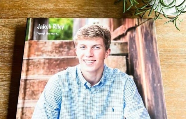 closed hard back photo book on wood table next to plant