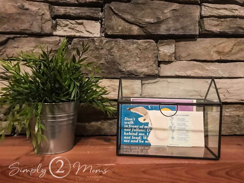glass box with letters displayed on mantel with faux plant