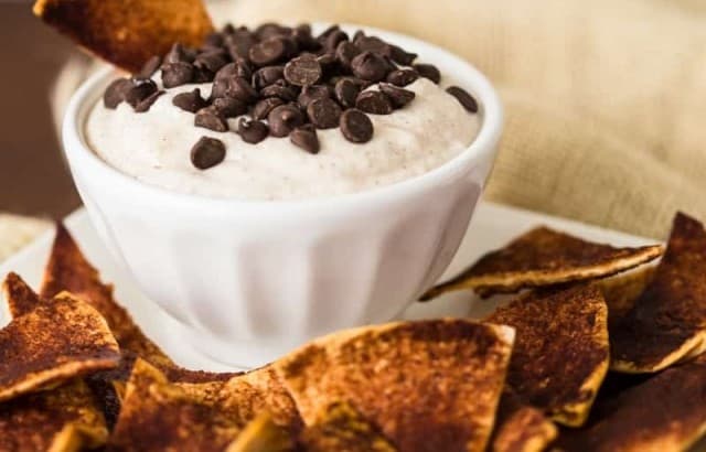 A bowl of cannoli cream topped with mini chocolate chips surrounded by low carb cinnamon crisps