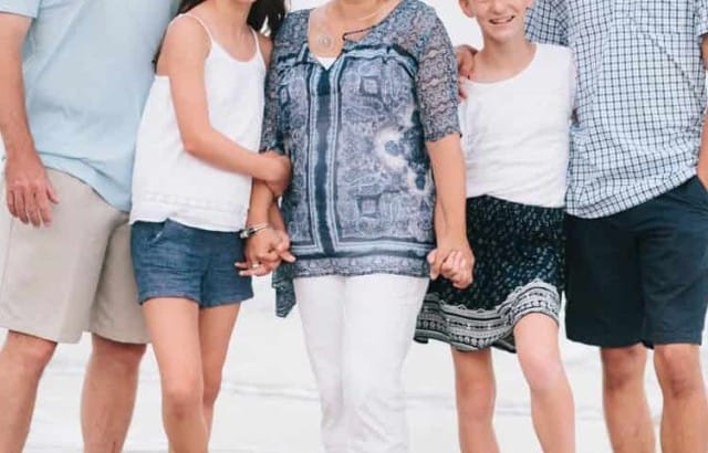 Family portrait taken on beach with family wearing shades of blue and navy