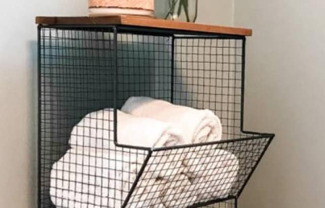 metal and wood basket storage tower filled with toilet paper and towels in bathroom