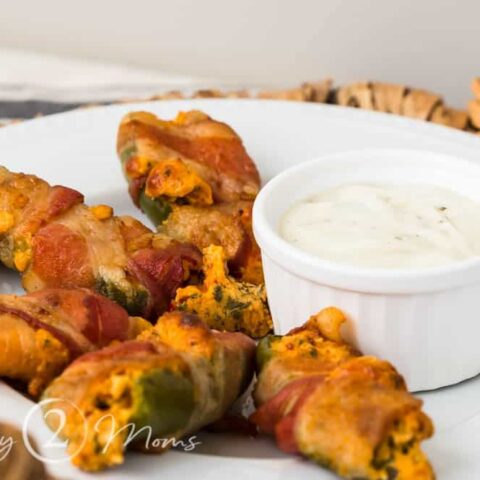 Bacon-wrapped BLT Jalapeno Poppers on a plate with a ramekin of ranch dressing