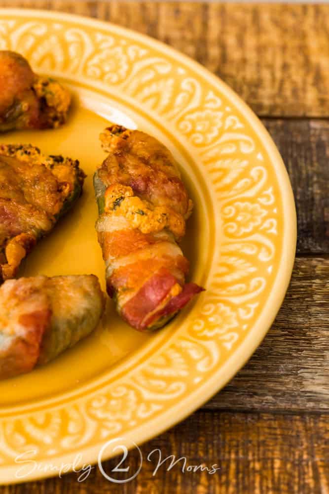 Bacon-wrapped BLT Jalapeno Poppers on a yellow plate on a rustic wood table