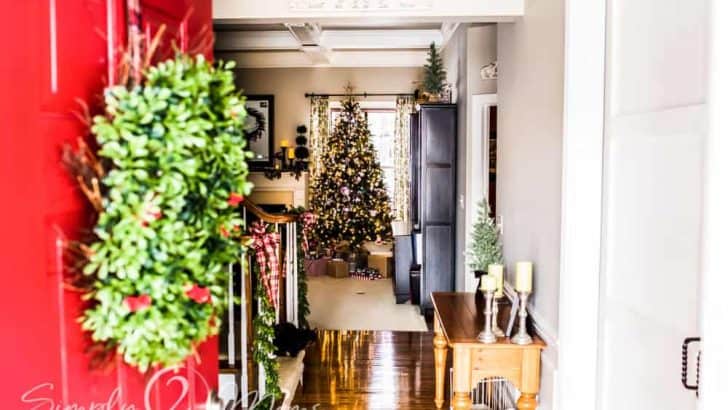 red door with green boxwood wreath opened to view of home decorated for Christmas