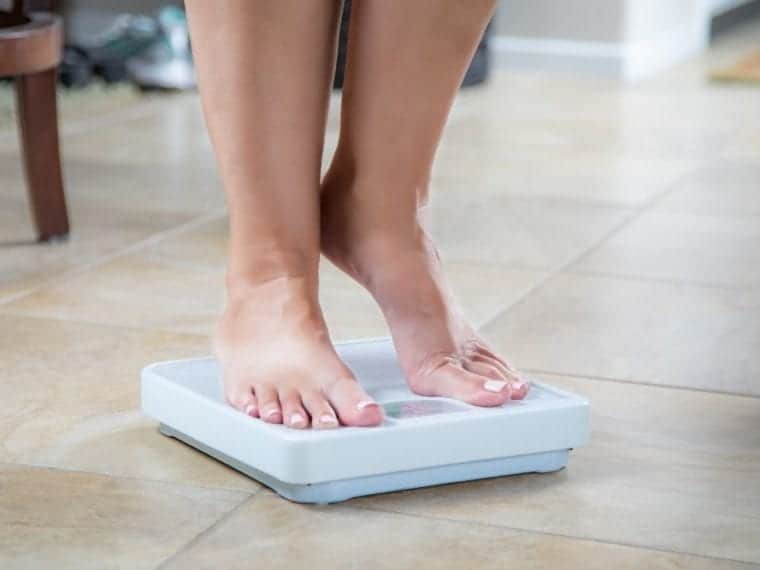legs and feet of a woman standing on a scale on tiptoes