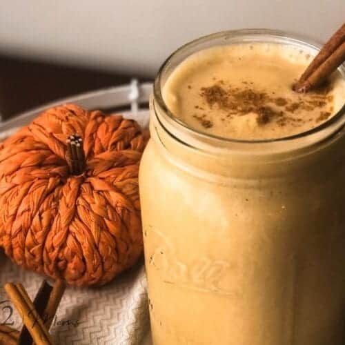 Overhead view of a large mason jar with a Pumpkin Spice Latte Custard Shake sprinkled with cinnamon and nutmeg with a stick of cinnamon on the edge.