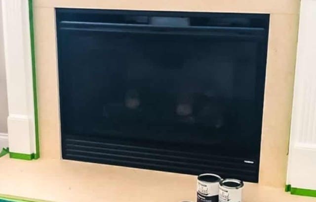 fireplace with marble surround taped with frog tape with cans of chalk paint