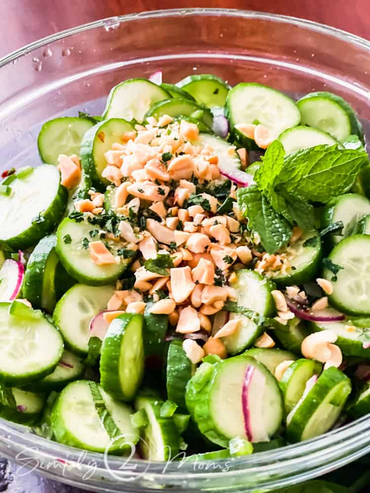 overhead view of glass bowl filled with Vietnamese cucumber salad garnished with chopped peanuts and fresh mint