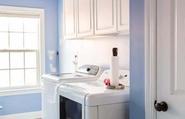 Laundry room with white cabinets with opening above holding cleaning supplies