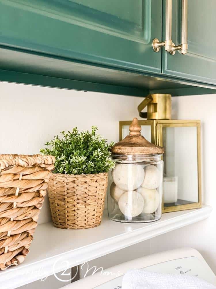 Shelf over washer and dryer with laundry room essentials and faux plants
