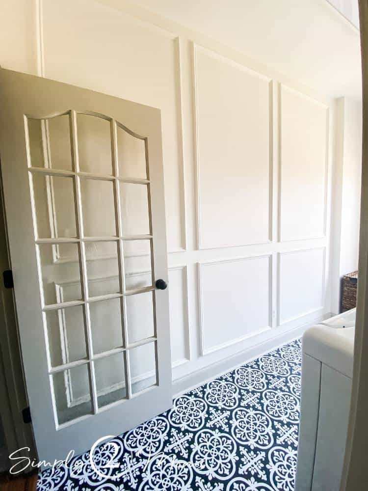 Laundry room with French doors and picture box moulding on the walls and peel and stick tiles with a hand painted ceramic tile look on the floor