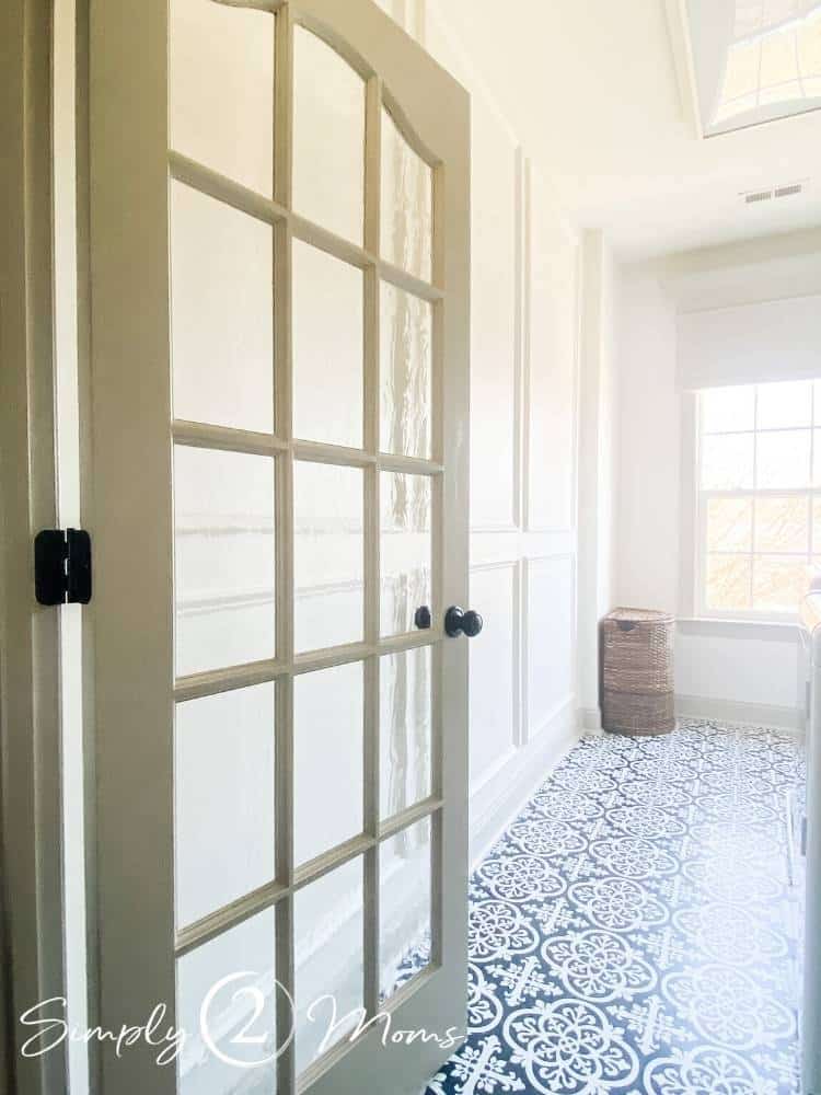 Laundry room with French doors and picture box moulding on the walls and peel and stick tiles with a hand painted ceramic tile look on the floor