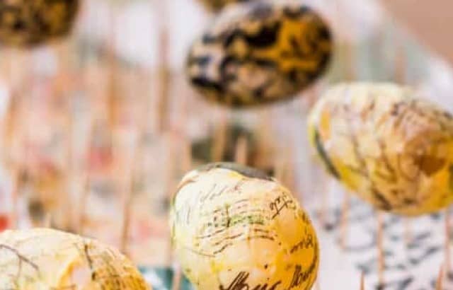 Decoupaged plastic eggs drying on a "rack" made from toothpicks in a box.