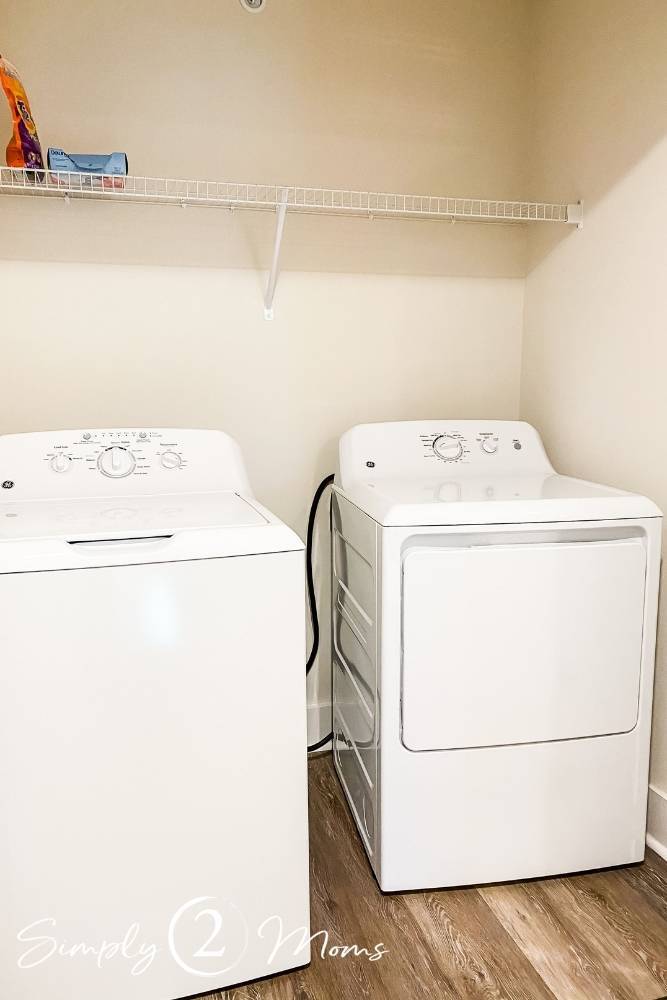 view of washer and dryer with wire shelf above on wall