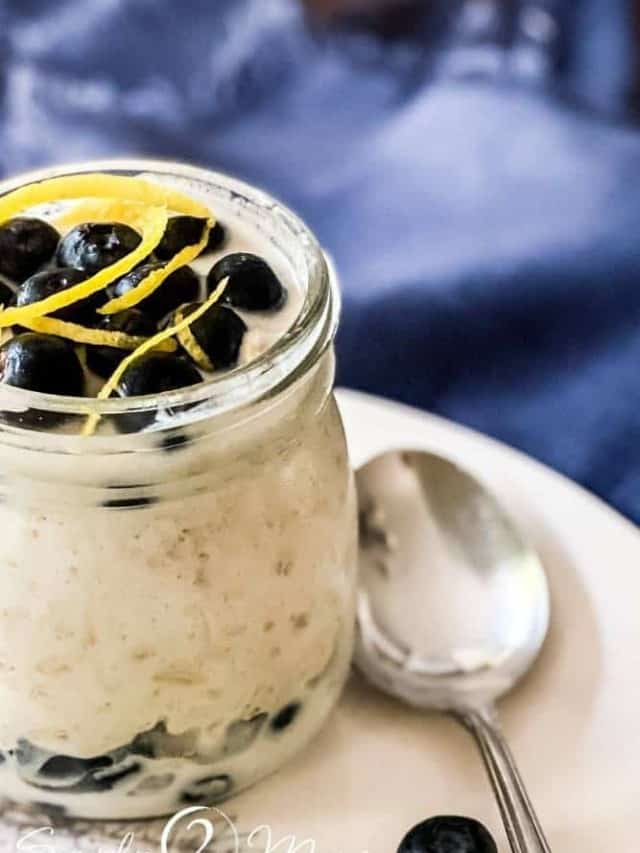 A single-serving jar of lemon blueberry overnight oats garnished with lemon zest with a spoon sitting next to it.