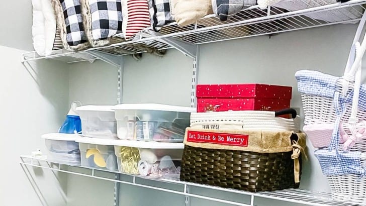 adjustable shelving on wall of walk in closet filled with bins and pillows