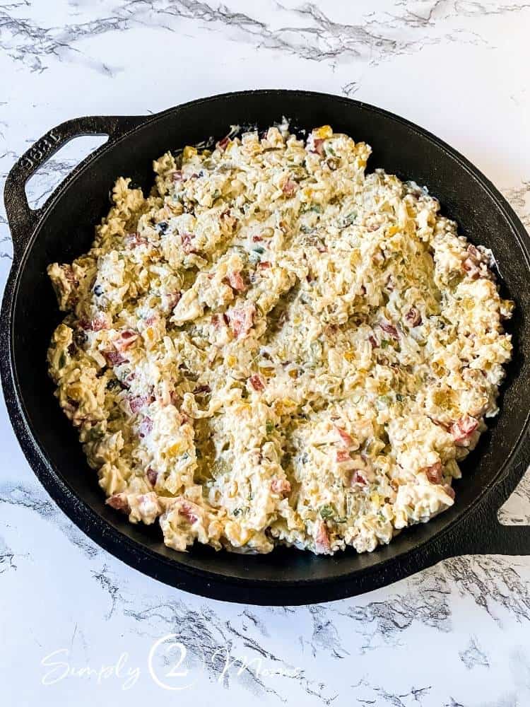 Cast iron skillet filled with roasted corn dip before baking