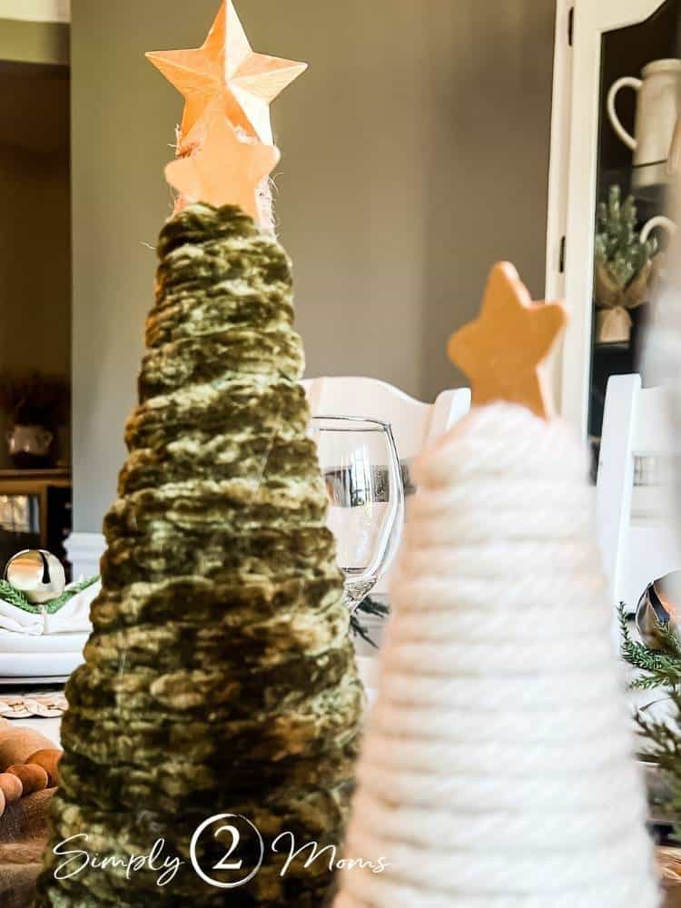 Close up of two chunky DIY yarn Christmas trees with gold stars on top
