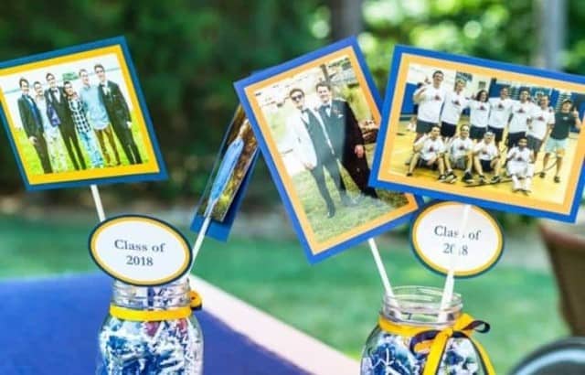 Large mason jars filled with crinkle paper and wrapped with ribbon at the top hold high school photos for a party decoration.