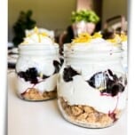 Small jars filled with low carb keto Blueberry Lemon Delight Parfaits on a table garnished with lemon zest