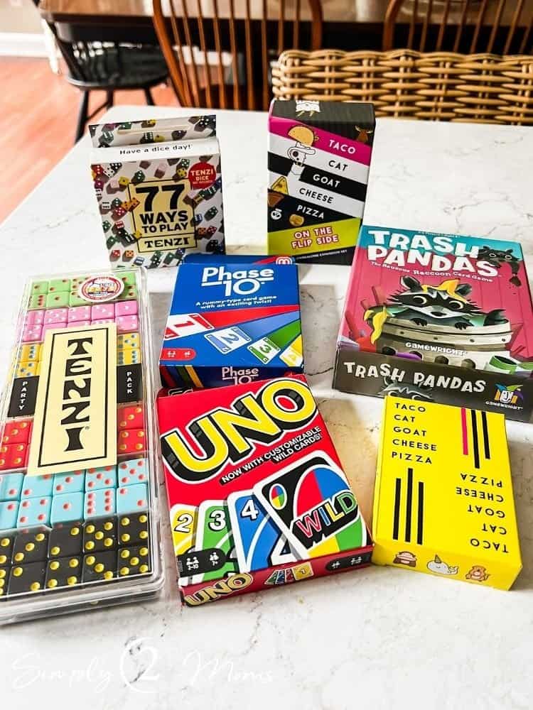 Assortment of games to take on a trip including Tenzi, Uno, Phase 10, Taco Cat, and Trash Pandas