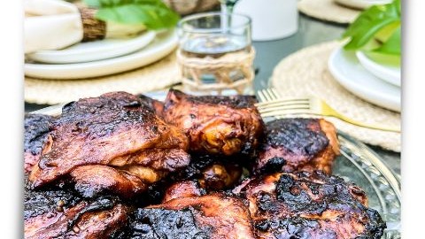 platter of grilled huli huli chicken on a table set for a backyard luau