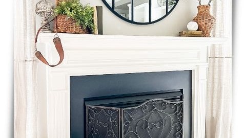 Traditional gas fireplace with white surround decorated for summer with wicker vase, greenery, and faux magnolias