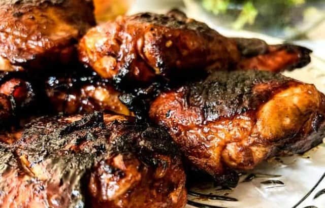 Platter of grilled sugar-free Huli Huli chicken with bowls of side dishes for a backyard luau