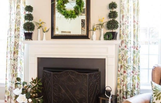 Gas fireplace with painted marble surround decorated for summer with boxwood topiaries