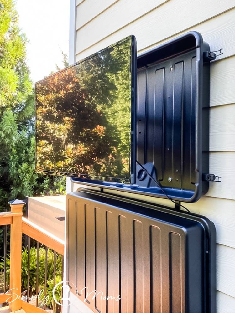 tv hanging outside on back of house outside in protective cover