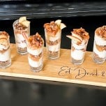 Shot glasses filled with keto caramel apple cheesecake parfaits on a custom wood board from PNW Farmhouse Design Co.