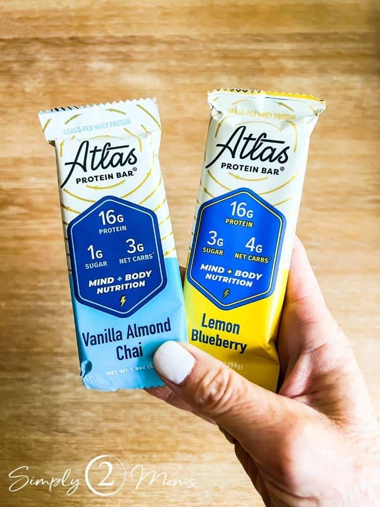 blogger holding two atlas bars vanilla almond chai and lemon blueberry