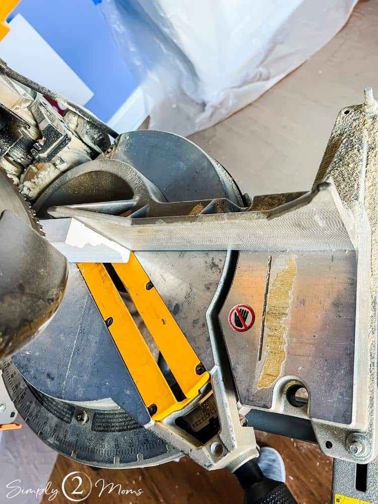 Overhead view of a miter saw set to a 45 degree angle and window casing positioned for a vertical cut.