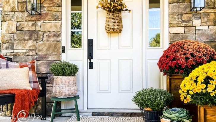 colorful fall mums decorate small porch with bench to side