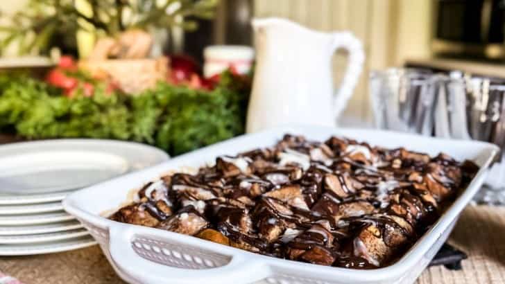 Christmas breakfast buffet with stack of plates, plaid napkins, and casserole dish of chocolate chip French toast.