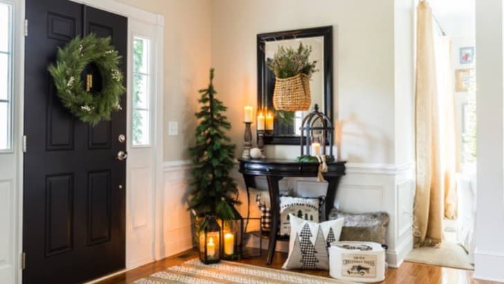 Farmhouse entryway table decorated for Christmas with wood lanterns, greenery, pillows and baskets.