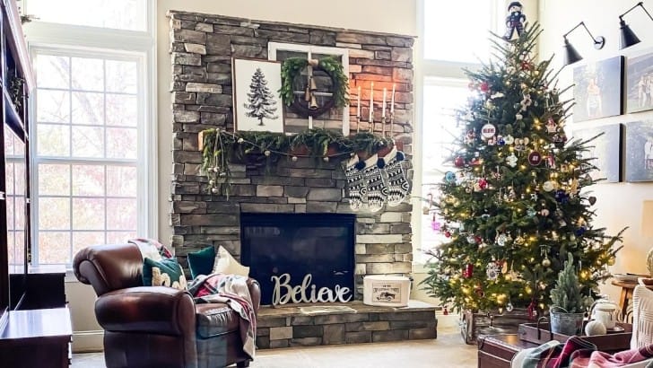 Family room with stacked stone fireplace decorated for Christmas with a live Christmas tree.