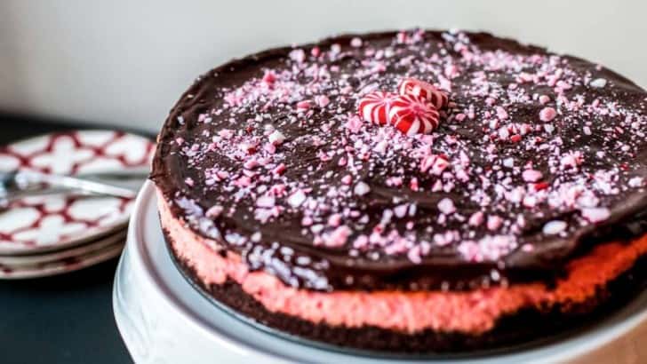 Keto Chocolate Peppermint Cheesecake on a cake stand garnished with crushed sugar free peppermint candies.