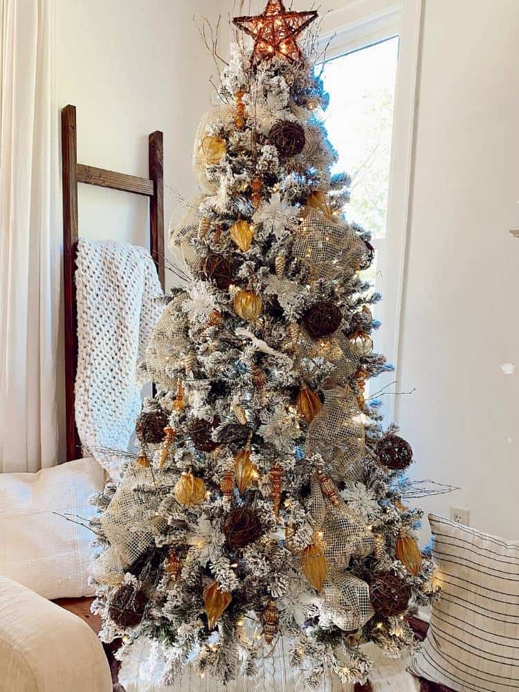 Flocked Christmas tree with pinecones and gold ornaments.