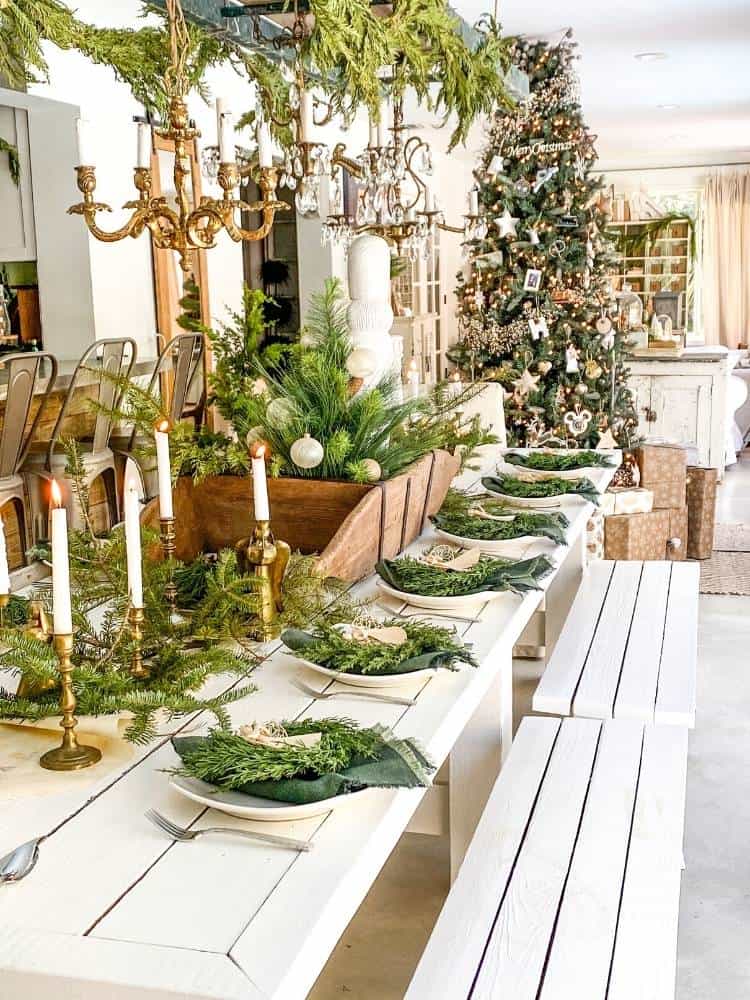 table set for Christmas dinner with greenery and gold candlesticks