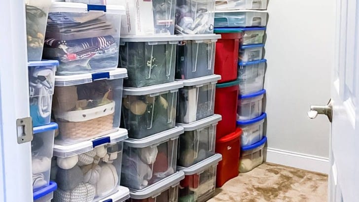 stacks of plastic storage totes in large closet of Christmas storage