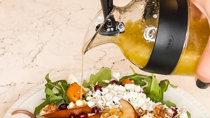 OXO homemade dressing container pouring Champagne Pear Vinaigrette over a salad.