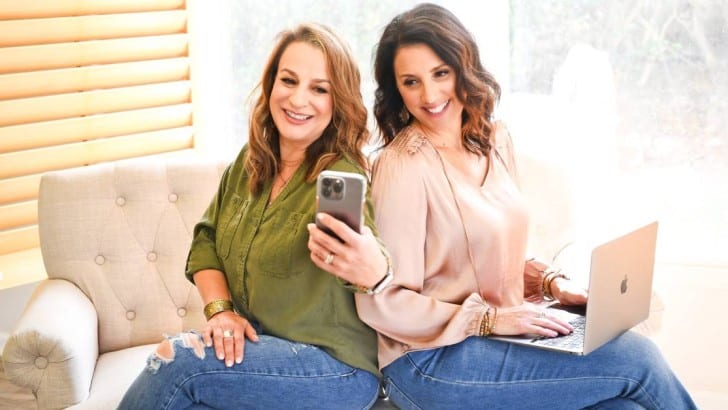 Anne and AnnMarie from Simply2Moms looking at a laptop and iphone to review most popular posts of 2022.