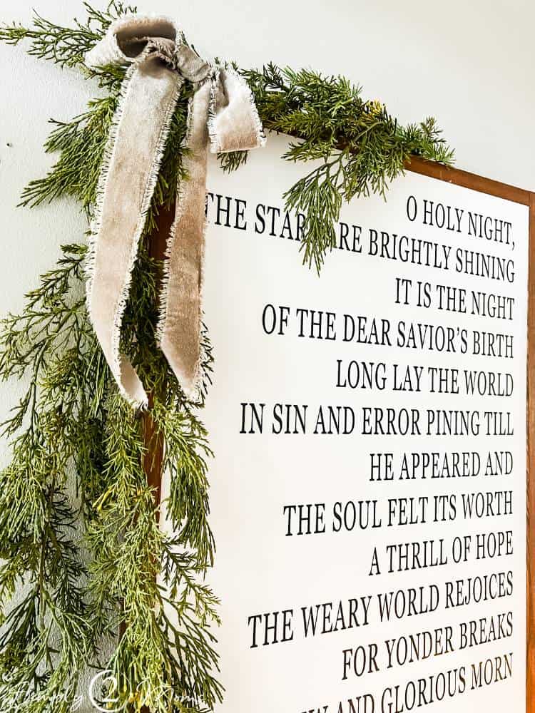 frayed edge ribbon tied to greenery hanging on corner of framed word art