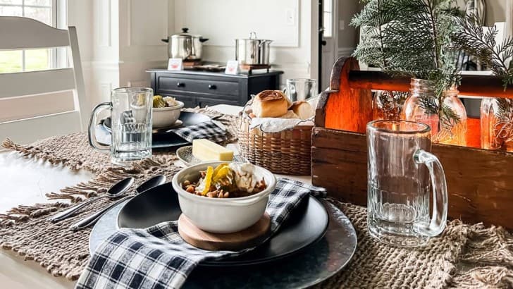 Table set for dinner with black plates, woven jute placemats, and crocks for a chili cook off.