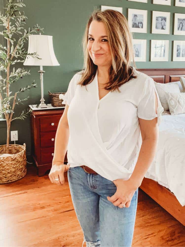 Woman wearing a white V neck blouse with short sleeves that tie at the ends of the sleeves.