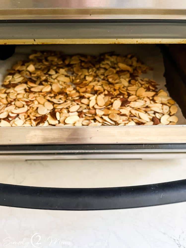 Tabletop air fryer toaster oven combo with a tray of sliced toasted almonds inside.
