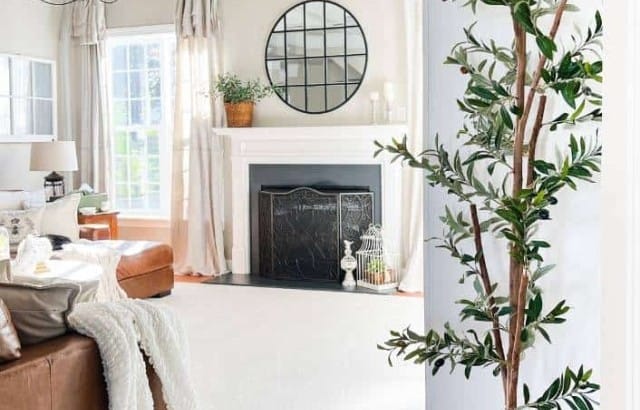 7 foot faux olive tree in a large basket by a white built in in a neutral family room decorated for spring and summer.